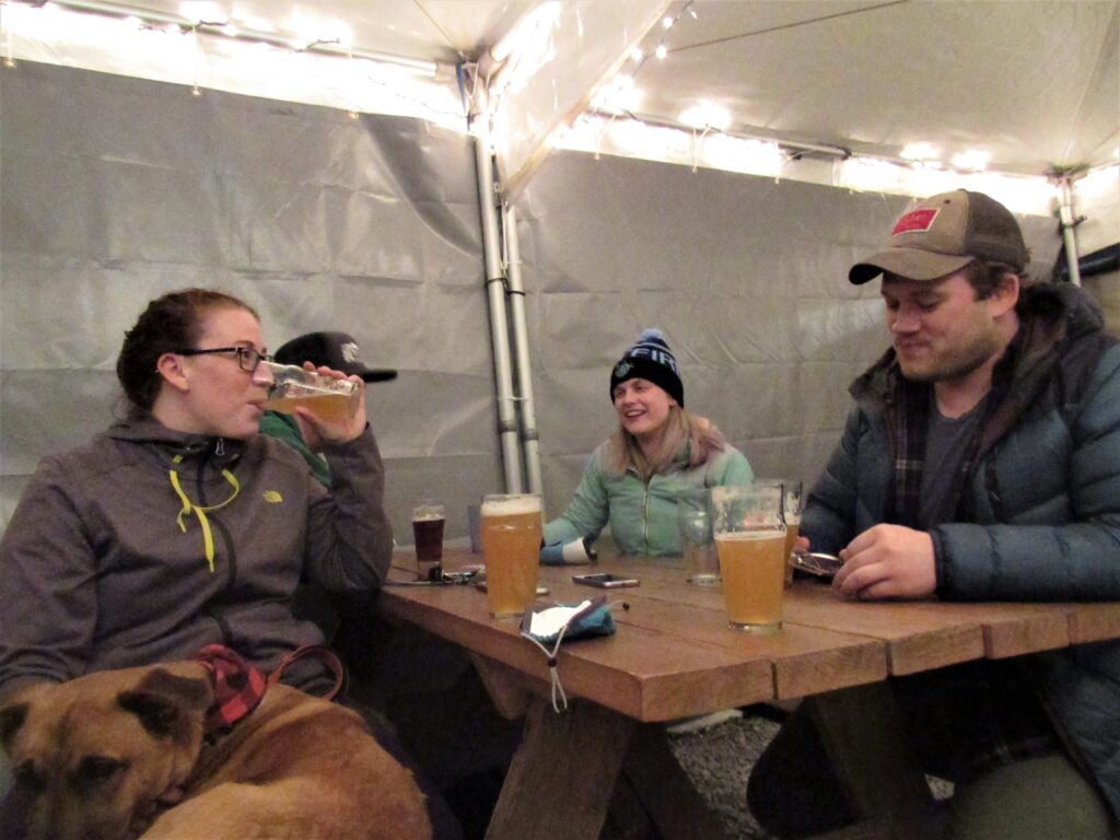 Four people sit at an outdoor patio at Fishers Brewing Company