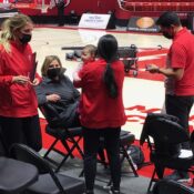 Malia Shoji works while holding her baby at the Huntsman Center.