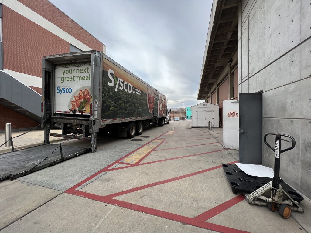 A Sysco semi delivery truck prepares for delivery behind Shaw Student Center.