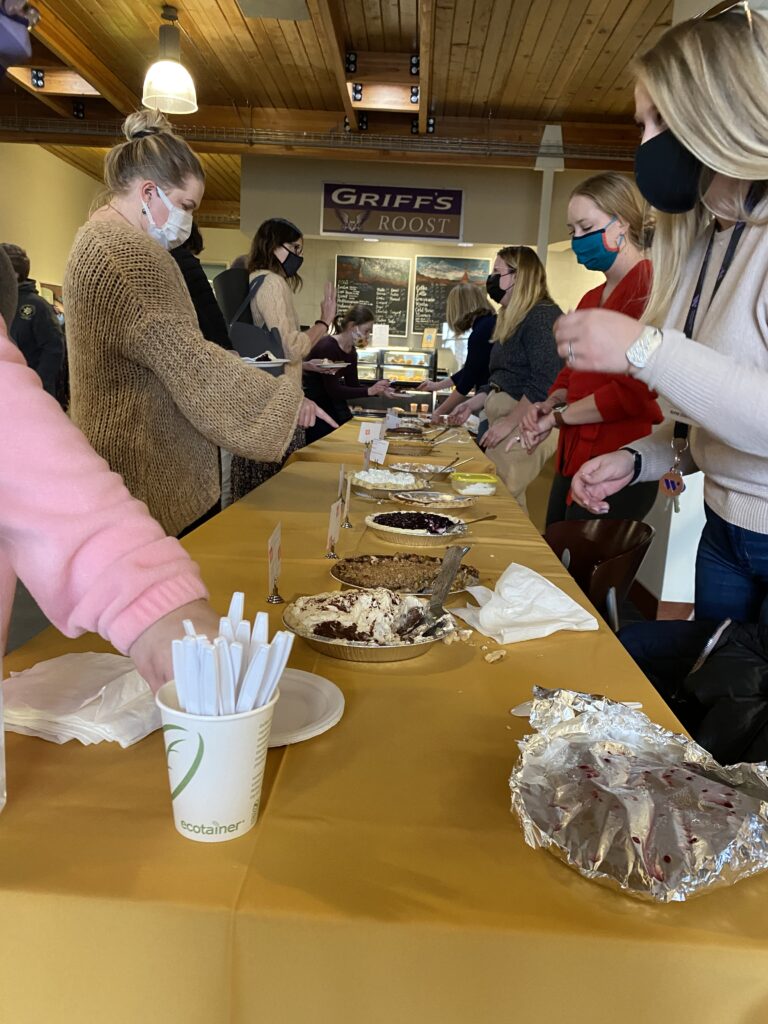 Members of the Westminster College staff serve pie from behind a long banquet table at the Annual Staff Council Pie Auction in Bassis Student Center.
