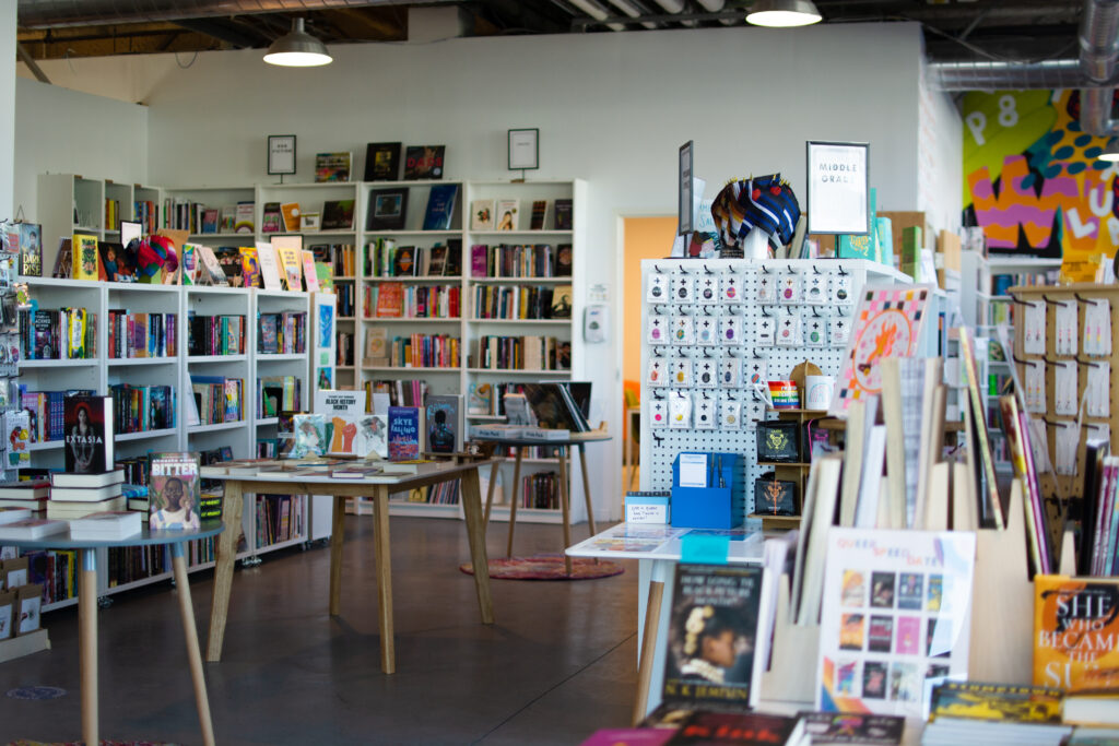 The main room of Under the Umbrella, a queer bookstore, displays hundreds of books, as well as art and other items from queer-owned businesses. 