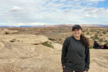 Shellby Carvalho, a female student, stands outside, poses on top of a rock structure in Canyonlands, Utah.
