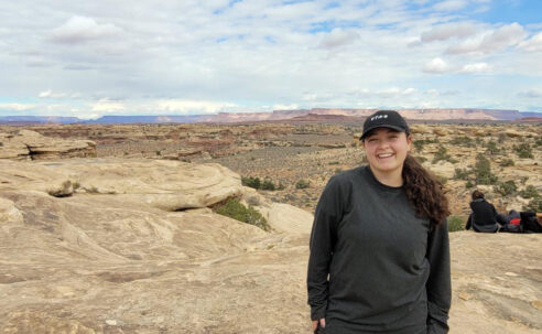 Shellby Carvalho, a female student, stands outside, poses on top of a rock structure in Canyonlands, Utah.