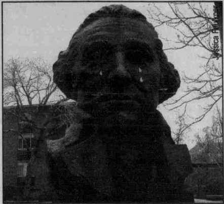 A grainy black and white photo shows a picture of George Washington's bust in front of some tree branches.